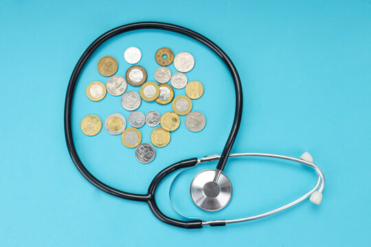 Closeup of Medical Stethoscope Encircling Scattered Coins on Blue Background
