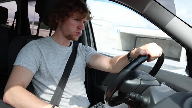 Young driver looks at his smartphone while driving then suddenly brakes after noticing danger ahead showing distracted driving and a serious road safety risk while moving