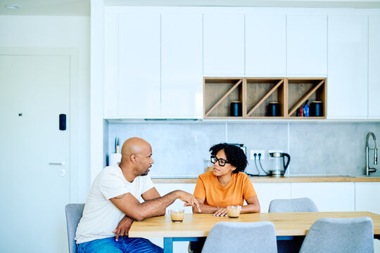 African American couple sitting at kitchen table, having an important conversation over coffee, discussing relationship issues