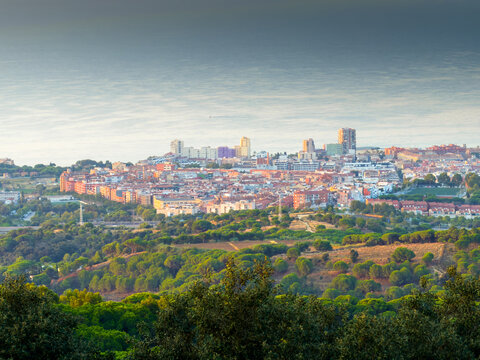 Scenic aerial panoramic view of Mataro coastal city in Catalonia Spain at sunrise, overlooking Mediterranean sea, forested green hills and urban skyline.