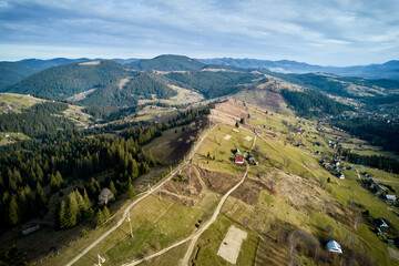 Naklejka premium Aerial view of stunning mountain landscape with rolling hills, dense forests, rural houses.