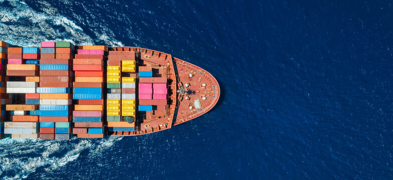 Aerial overhead view of a the bow of a container cargo ship in motion over ocean as a banner for transport and industry with copy space