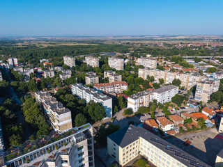 Fototapeta premium Elevated panoramic view of Vidin, Bulgaria, featuring residential apartment blocks, a tree-lined boulevard and the urban landscape extending toward the horizon on a sunny summer day. Drone view