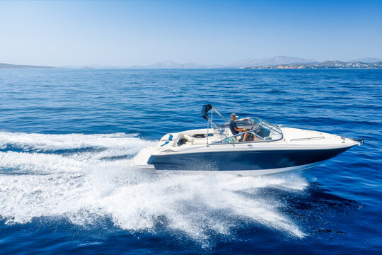 Aaerial view of a motorboat cruising with high speed over the ocean and leaving a trail of surf and waves behind
