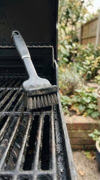 Wire brush scrubbing a charred outdoor barbecue grill