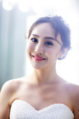 Fototapeta premium An elegant East Asian bride, dressed in a luxurious white lace long-sleeved wedding dress, was photographed up close.