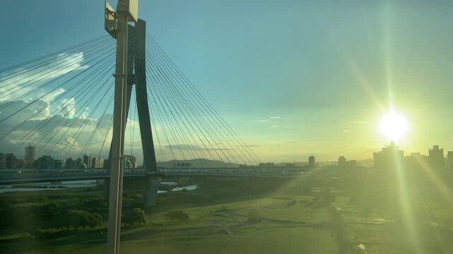 Scenic view of a modern cable-stayed bridge and city skyline from an airport train window at sunset in Taiwan 대만 타오위안 공항철도(MRT)