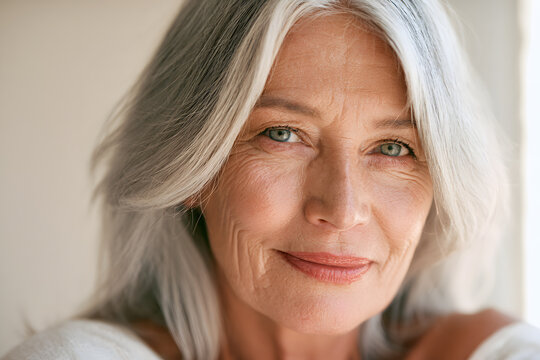 A smiling elderly woman, with gray hair and wrinkles, has a healthy glow and expressive face, captured in a close-up portrait under natural light