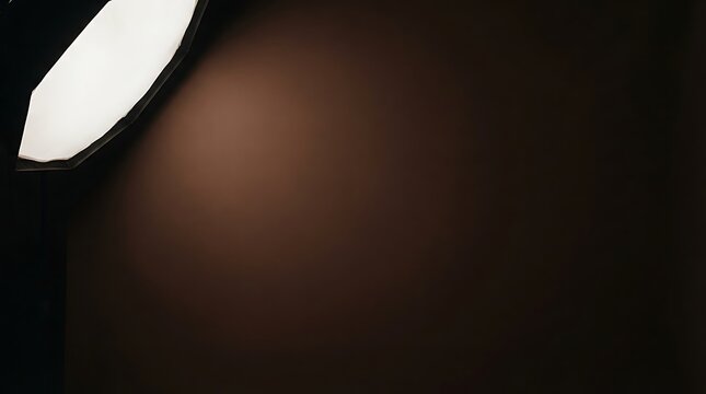 Professional photography softbox illuminating a dark studio background with a soft, warm light gradient.
