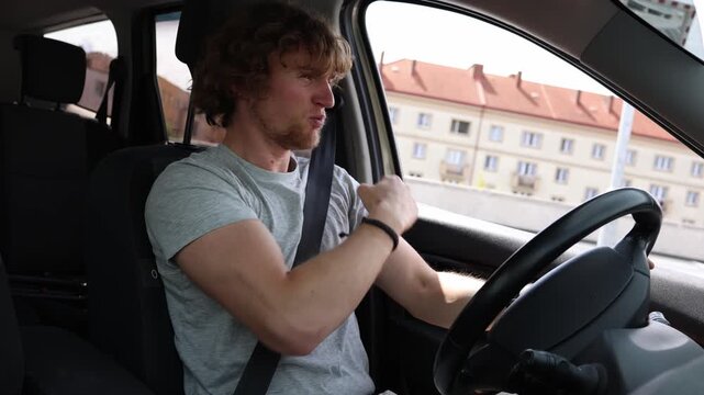 Angry young driver shows his fist at another motorist while driving through the city expressing road rage and aggression after becoming frustrated by city traffic on road
