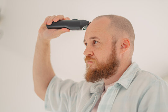 Close up of a man giving himself a buzz cut at home