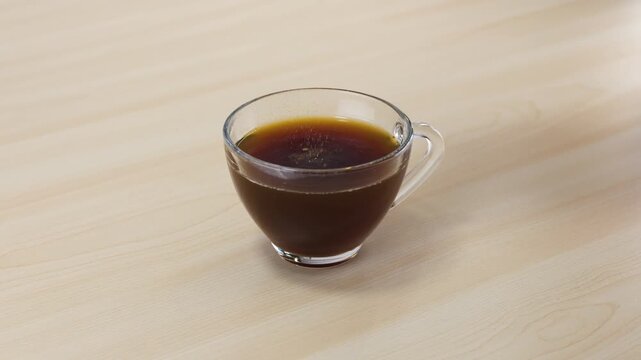 Instant Coffee Powder Falling into Glass Cup of Hot Water