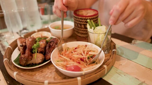 Person Eating Thai Papaya Salad and Grilled Chicken in Bangkok