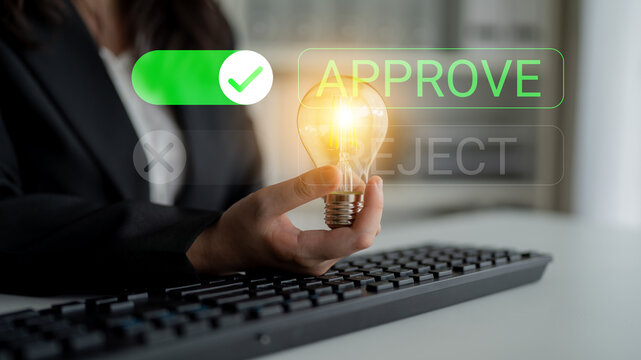 Business professional holding glowing light bulb symbolizing approval and creative ideas in modern office setting with keyboard in foreground. Glyphic.