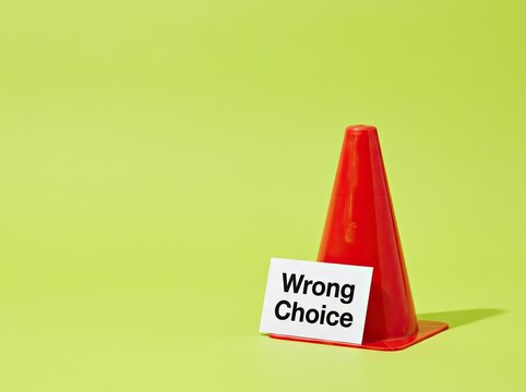 Orange traffic cone with Wrong Choice card on green background suitable for decision making visual symbolizing bad decisions and caution