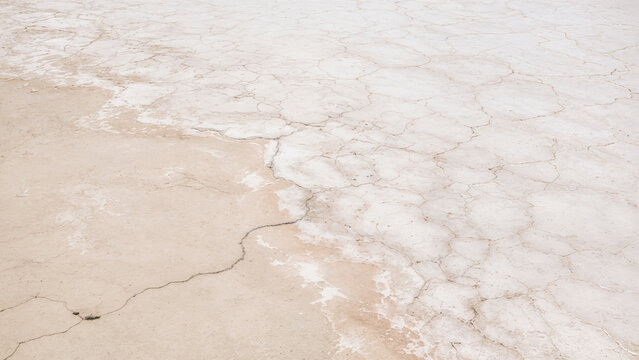 The ground shows vast areas of dry salt flats with visible cracks and patterns, creating a distinct landscape. This scene captures the texture of arid land during the day