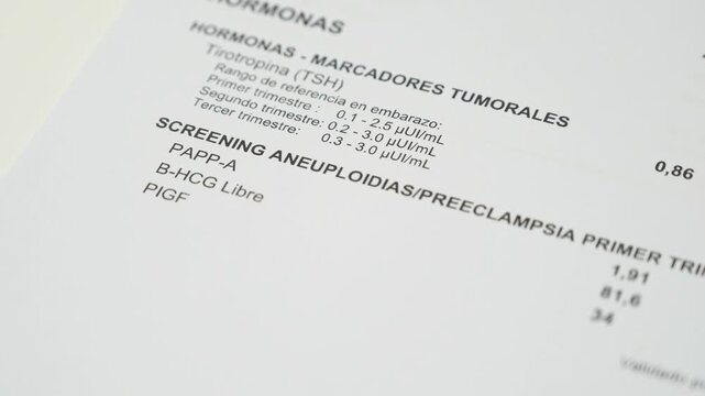Close up of person marking tsh papp-a and hcg hormone test results on paper