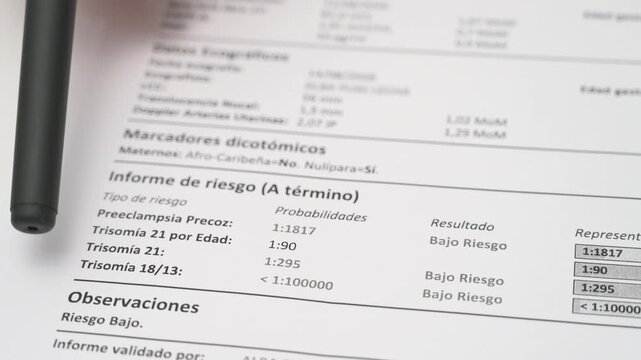Close up of pen pointing at pregnancy screening report with risk bar chart