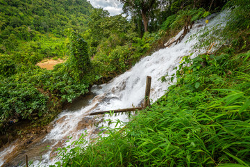 Scenic limestone cascading waterfall at Naw Ta or No Taw in Karen State, Myanmar, surrounded by lush green tropical forest, natural mountain cliff, and flowing stream in daylight. © Around Ball
