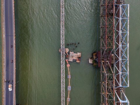 Aerial View of Three Parallel Bridges Carrying Road Traffic, Water Pipeline Infrastructure, and Railway Tracks Across a River in Indonesia. Distinct Transportation Infrastructure, Captured from Above.