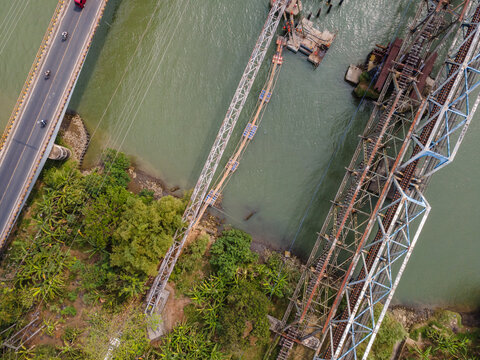 Aerial View of Three Parallel Bridges Carrying Road Traffic, Water Pipeline Infrastructure, and Railway Tracks Across a River in Indonesia. Distinct Transportation Infrastructure, Captured from Above.