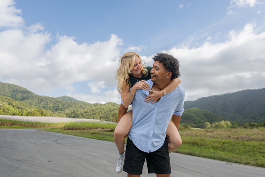 Young mixed race couple smiling and in love during a piggyback ride