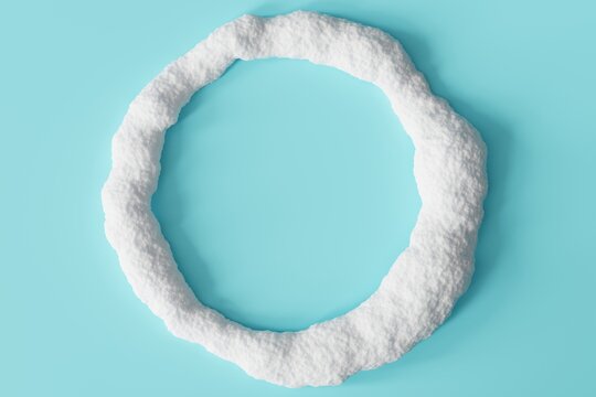 A round frame made of white snow sits on a flat light blue surface. There is space inside the frame for text or captions. The snow appears fluffy and textured