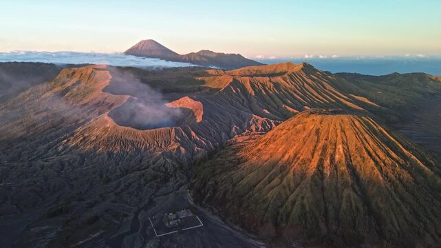 Close drone flight toward Mount Bromo and surrounding volcanic peaks in vibrant red dawn light, revealing Mount Semeru and the Tengger caldera, Indonesia