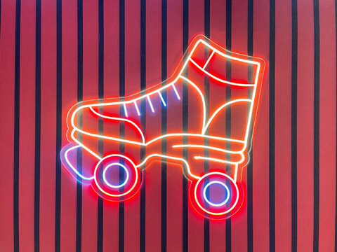 Retro neon roller skate glowing against a colorful striped background, creating a vibrant nostalgic sports and entertainment concept.