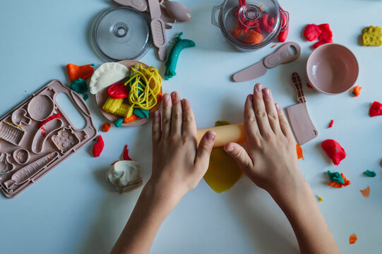 A boy rolls play dough with a toy kitchen set indoors