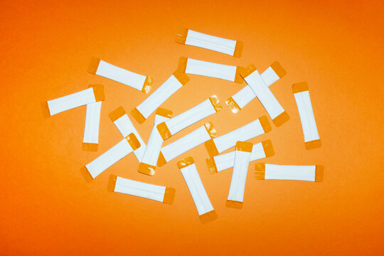 White supplement packets lie scattered on an orange background