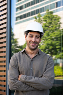 Smiling architect wears a white helmet outdoors