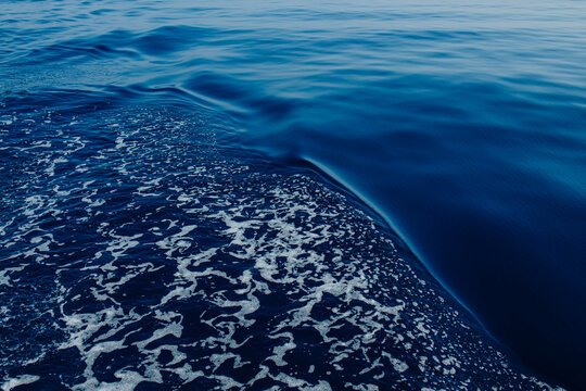 A sailboat leaves a white foam wake on the blue Mediterranean sea