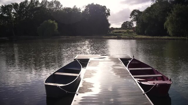 Wooden pier with moored rowing boats on calm lake