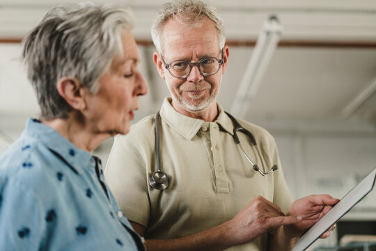 Male doctor explains diagnosis to female patient indoors