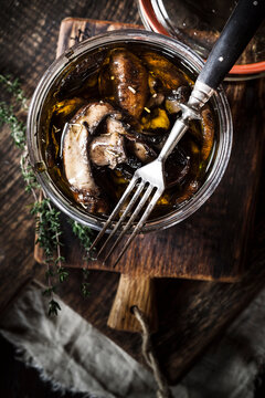 Preserving jar of pickled champignons with herbs