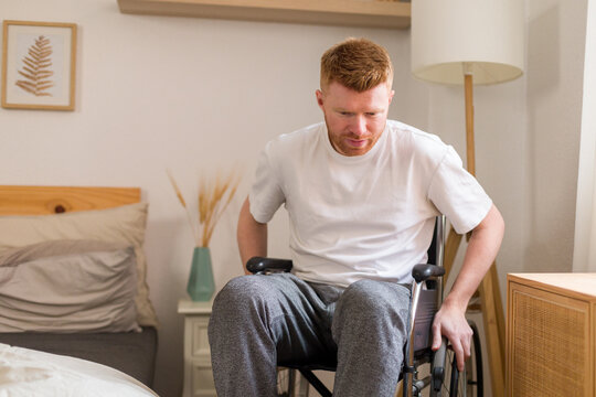Man in wheelchair practicing independent living in bedroom at home