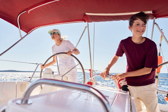 Mother and teenage son sailing a sailboat on the ocean in Croatia