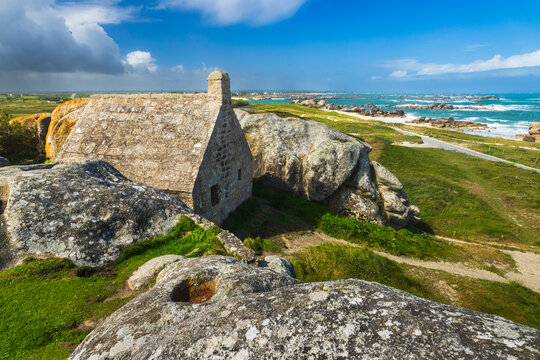 Solitary stone house stands among granite rocks on the Brittany coast