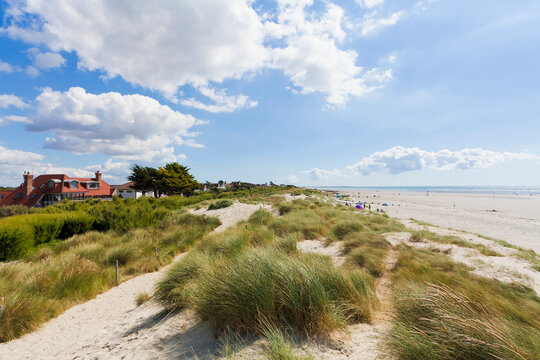 Sand dunes border a wide beach near mansions in West Wittering