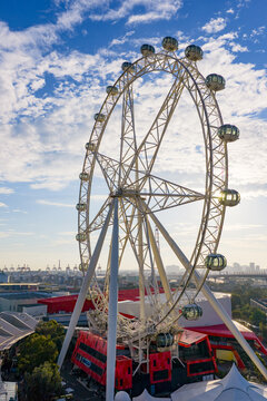 Gondola capsule around the edge of a large sight seeing ferris wheel against a city backdrop