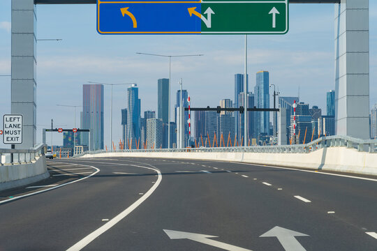 View along a multi-laned freeway with overhead signage toward a city skyline