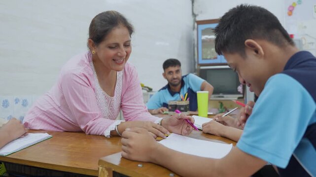 Caring female special education teacher providing one-on-one assistance to a student with learning disabilities, guiding his hand as he practices writing in a supportive classroom setting