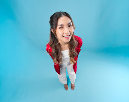 Happy young Asian woman in a red jacket is standing and posing smiling to the camera.