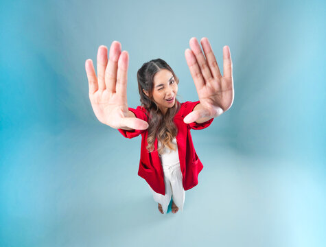 Cheerful young Asian woman is posing a playful gesture and expression to the camera.