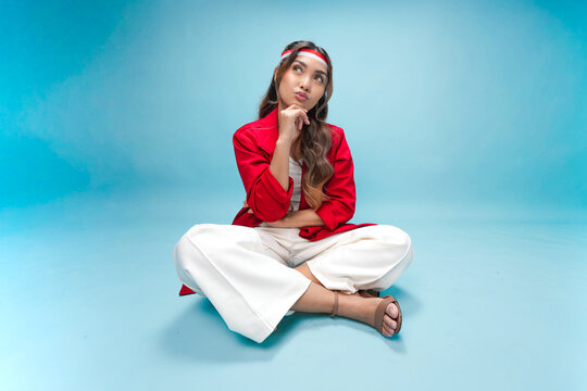 Confused young Indonesian woman is sitting on the floor and thinking hard for an idea.
