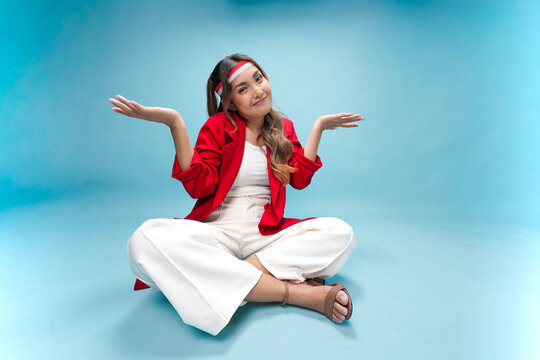 Confused young Indonesian woman is sitting on the floor and thinking hard for an idea.