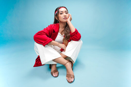 Beautiful young Indonesian woman is sitting on the floor and posing to the camera.