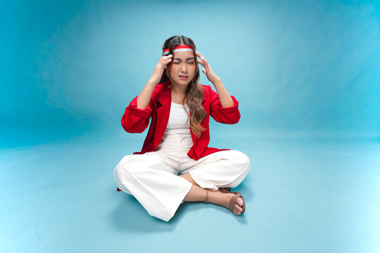 Confused young Indonesian woman is sitting on the floor and thinking hard for an idea.