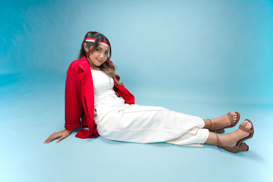 Pretty Indonesian woman is sitting on the floor and posing smiling to the camera.